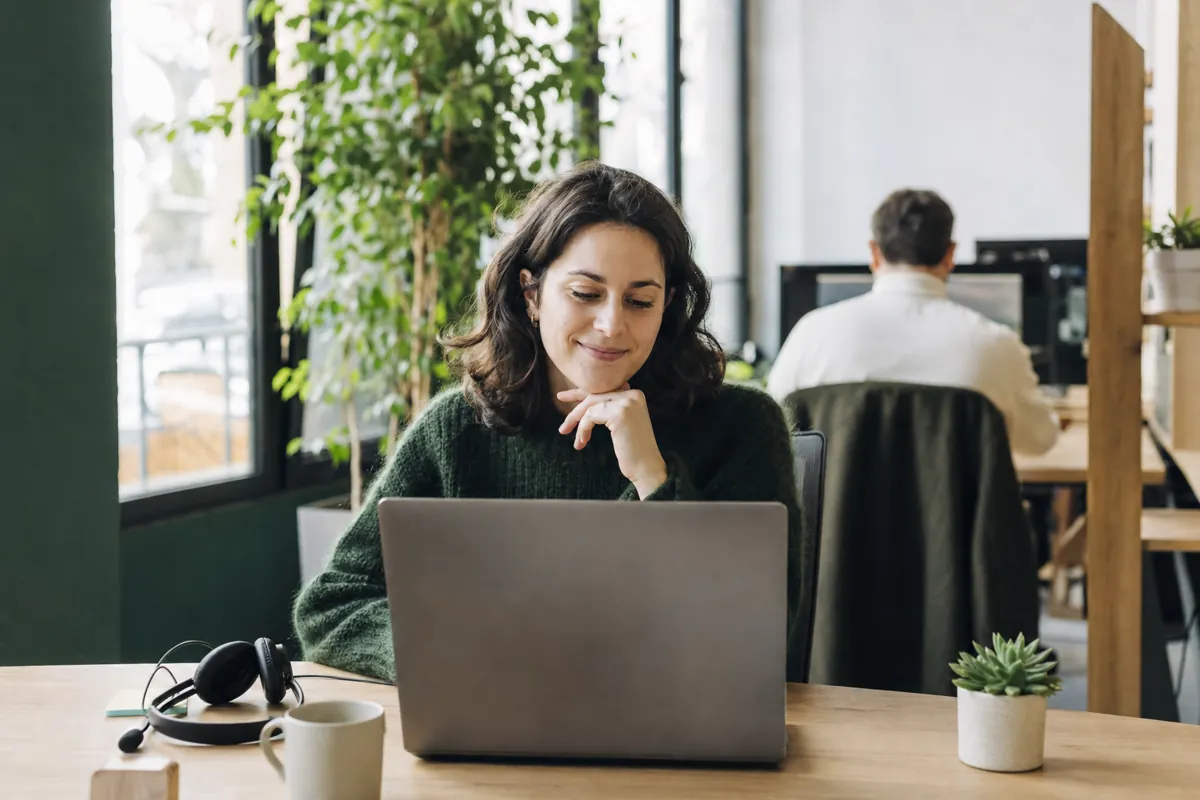 Une commerciale consulte sa liste de prospects à son bureau, le casque posé à côté d'elle
