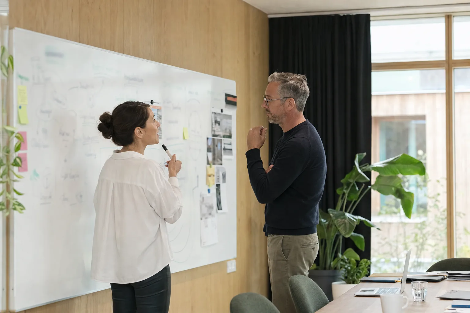 Deux personnes travaillent devant un tableau couvert de notes